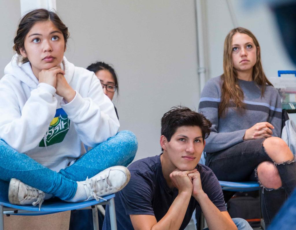 Students sitting in a classroom, listening attentively