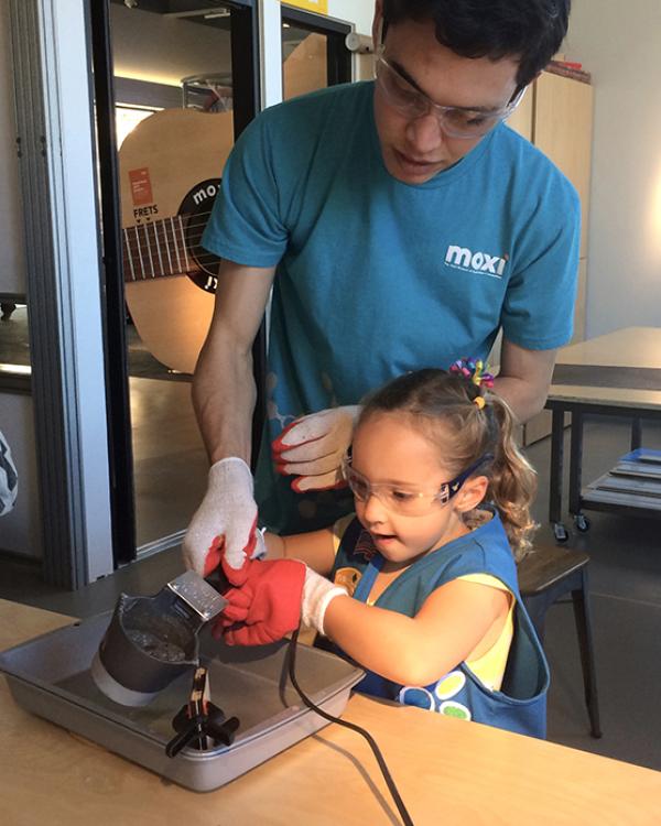 apprentice works with a child at MOXI 