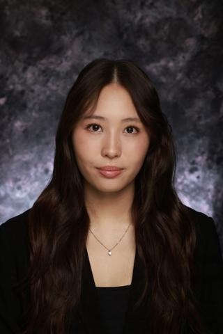 Ellen wearing a black blazer and black shirt, her hair is long and parted down the middle