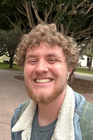 sam wearing jean jacket and smiling